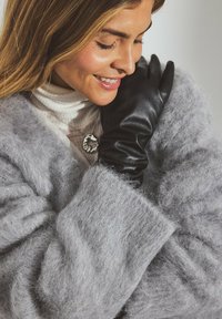 Black leather gloves with a smooth texture, worn with a soft, fluffy gray sweater. The sweater has oversized sleeves, creating a cozy look.
