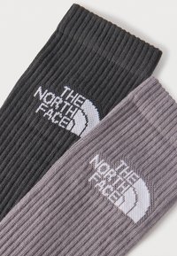 Δύο καλτσάκια με ριμπ, ένα σκούρο γκρι και ένα ανοιχτό γκρι, το καθένα με το λογότυπο «THE NORTH FACE» σε λευκό κοντά στην κορυφή.