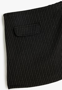 Jupe en tissu noir avec des rayures verticales blanches, dotée d'une petite poche plaquée, texture lisse et ourlet délicatement drapé.