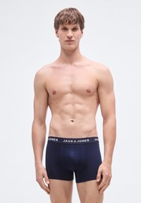 Mörkblå boxershorts med ett stretchigt midjeband som har texten "JACK & JONES". Tyget verkar slätt med en figursydd design.