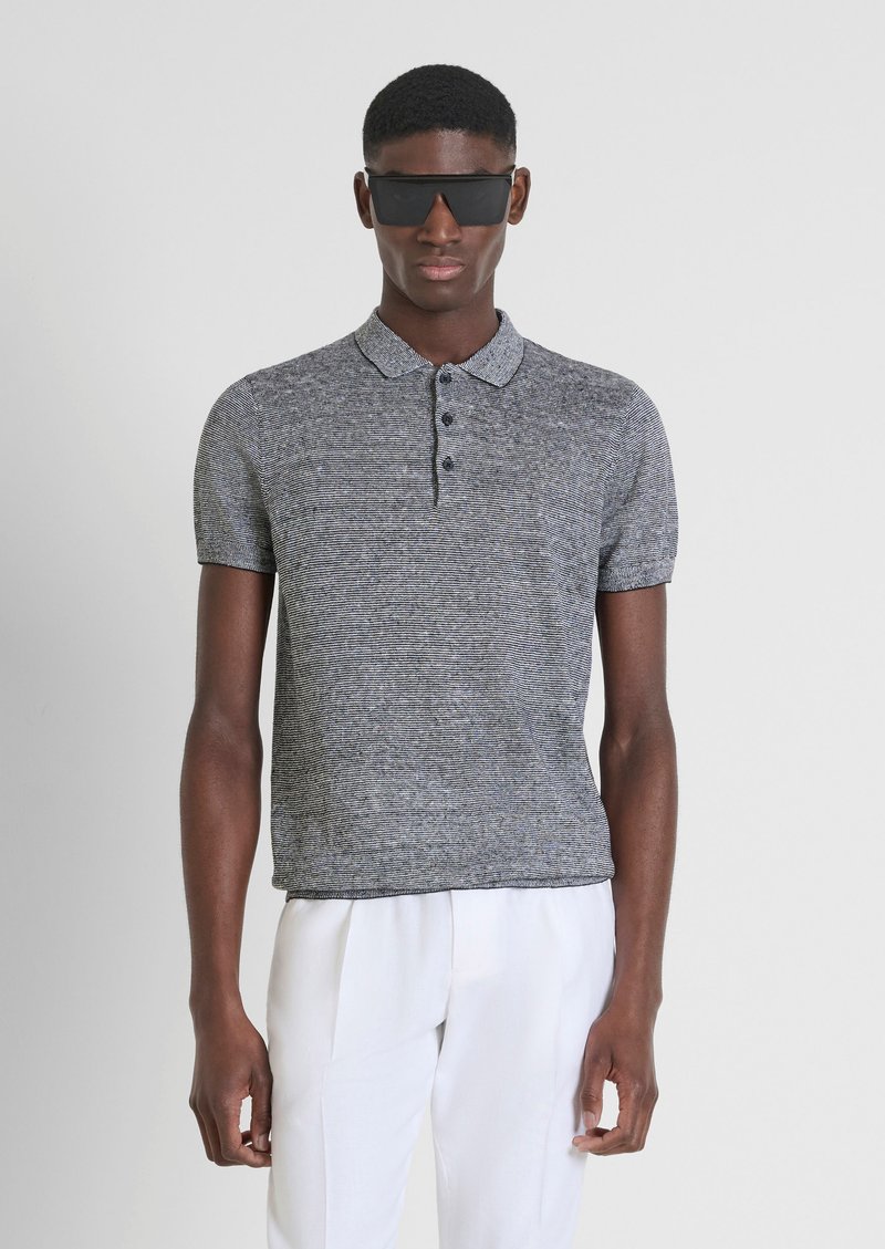 Polo shirt grigio a righe con colletto, a maniche corte e placca con tre bottoni. Il modello indossa occhiali da sole neri e pantaloni chiari.