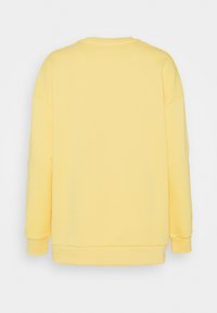 Sudadera amarilla con escote redondo, mangas largas y un corte relajado. Tejido de algodón suave, sin adornos ni patrones.