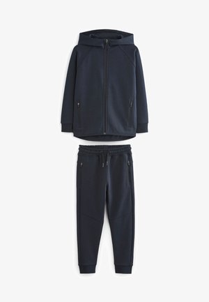 Marineblaues Kapuzensweatshirt mit Reißverschluss und zwei Seitentaschen, kombiniert mit passenden Jogginghosen, die einen elastischen Bund und Taschen haben.