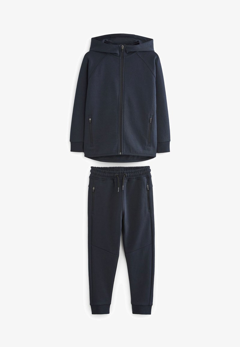 Granatowy wciągany sweatshirt z kapturem i zamkiem, z dwiema bocznymi kieszeniami, zestawiony z pasującymi spodniami dresowymi z elastycznym pasem i kieszeniami.
