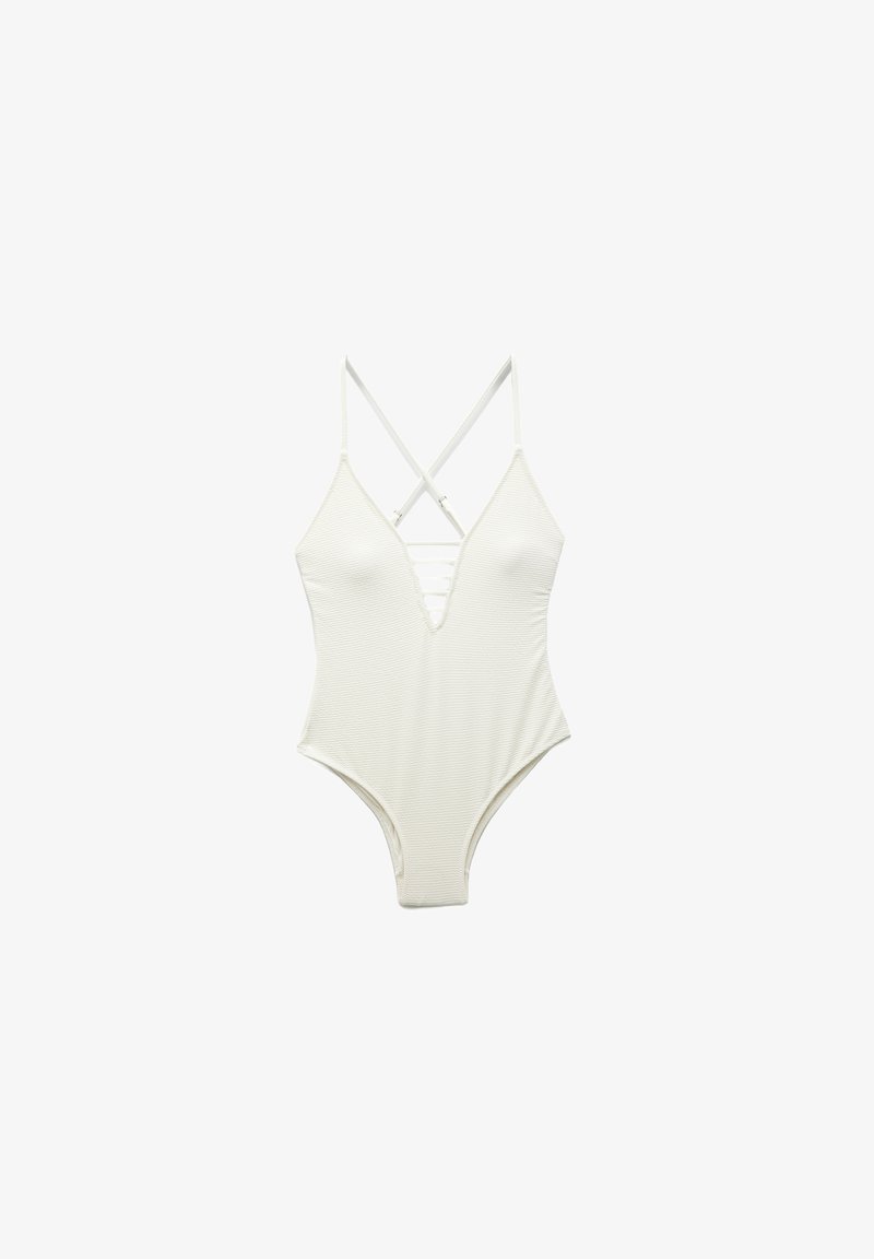 Maillot de bain une pièce blanc avec des bretelles croisées, décolleté en V profond, texture côtelée et jambes échancrées. Présente un détail à lacet à l'avant.