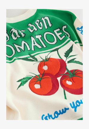 Džemperis ar trim sarkaniem tomātiem un zaļām lapām uz krēmkrāsas fona, papildināts ar zaļu un zilu tekstu. Mīksts audums un adīta dizains.
