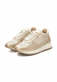 Zapatillas perforadas beige con un acabado metálico texturizado, cordones blancos y una suela de goma con un sutil acento dorado en el talón.