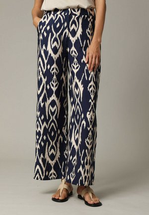 Pantalons large à motifs navy et crème en tissu léger avec un bold design ikat et des poches. Fini avec une ceinture lisse.