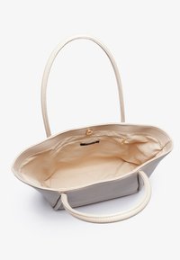 Beige läder toteväska med dubbla handtag, öppen topp och en mjuk interiör. Har ett litet dragkedjafack och sömdetaljer.