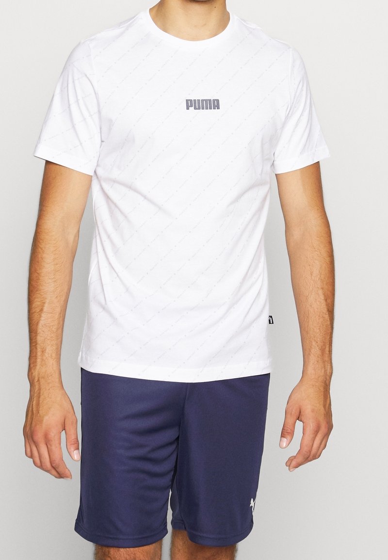 Bílý tričko s krátkým rukávem a texturovaným vzorem s šedým logem Puma na hrudi, kombinované s námořnickými šortkami s bílým logem.