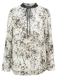 Blusa a maniche lunghe color crema con motivo a macchie nere e marroni. Presenta un colletto rotondo, un dettaglio con fiocco e un orlo leggermente asimmetrico.