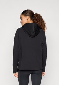 Μαύρο φούτερ με κουκούλα, ομαλή υφή, μακριά μανίκια και λεπτομέρειες ραφής. Διαθέτει άνετη εφαρμογή και τσέπη καγκουρό.