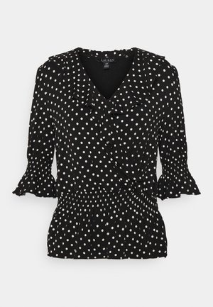 Zwarte blouse met witte polkadots, rucheslange V-halskraag, driekwart pofmouwen met geplooide manchetten en een geplooide elastische taille.