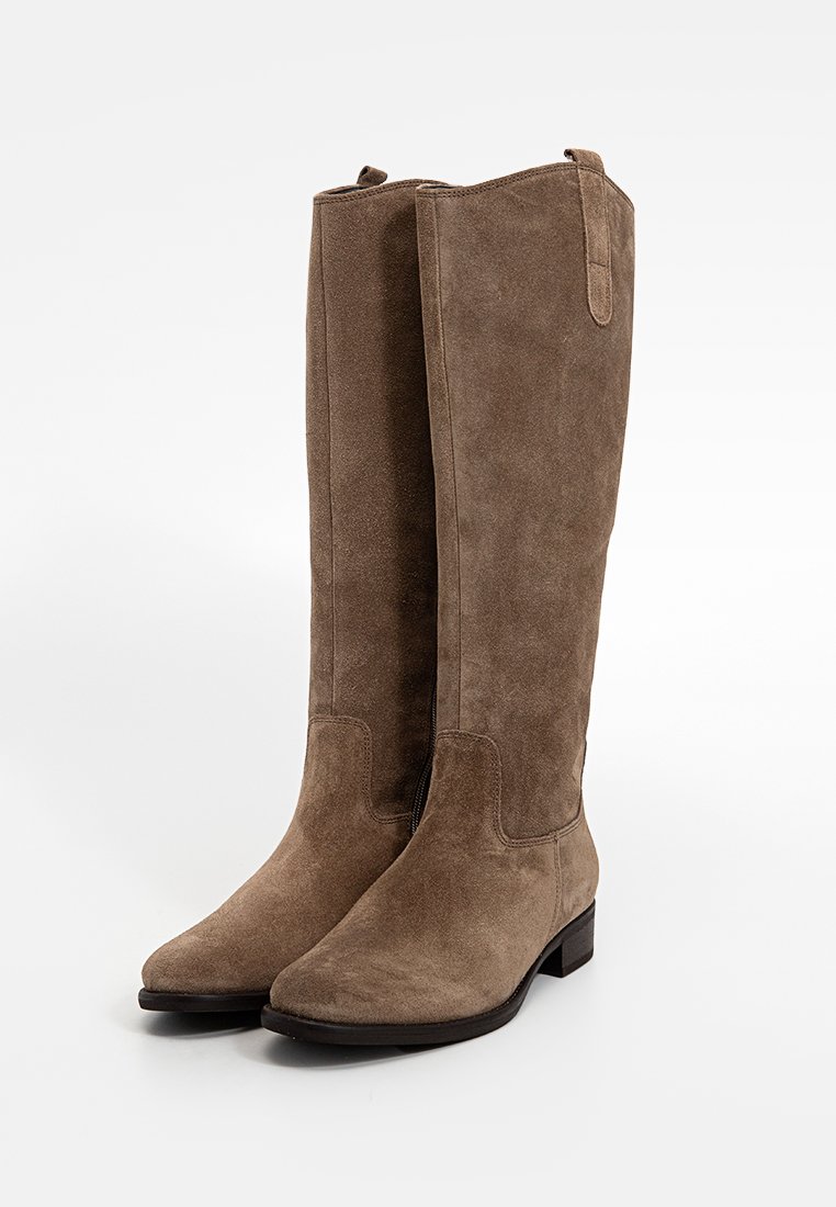 Bottes en suède marron jusqu'aux genoux avec un talon plat, présentant une texture lisse, des coutures minimalistes et une sangle de tirage pour faciliter l'enfilage.