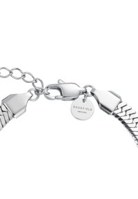 Pulsera de cadena de plata con cierre de langosta y pequeña etiqueta circular grabada con "ROSEFIELD AMS | NYC" sobre un fondo blanco.