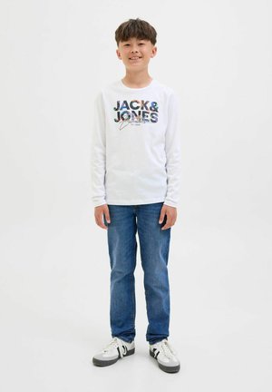 Camiseta blanca de manga larga con gráfico "JACK & JONES" en multicolor. Combinada con jeans azules y zapatillas gris-negro con acentos blancos.