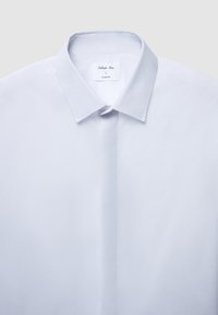 Camicia slim fit azzurro chiaro con colletto classico, abbottonatura e tessuto liscio e strutturato; etichetta visibile con dettagli su taglia e vestibilità.