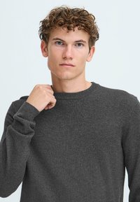 Grijze gebreide trui met een ronde hals en lange mouwen, die een zachte textuur en een slim fit ontwerp toont. Eenvoudige en veelzijdige uitstraling.