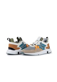 Chaussures de sport avec une tige en maille grise, des accents en daim marron, des détails turquoise et orange, une semelle blanche et un onglet de talon noir.