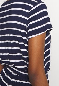Tmavě modré a bílé pruhované tričko s krátkými rukávy, měkký materiál a volný střih, s kulatým výstřihem a diskrétním švem.