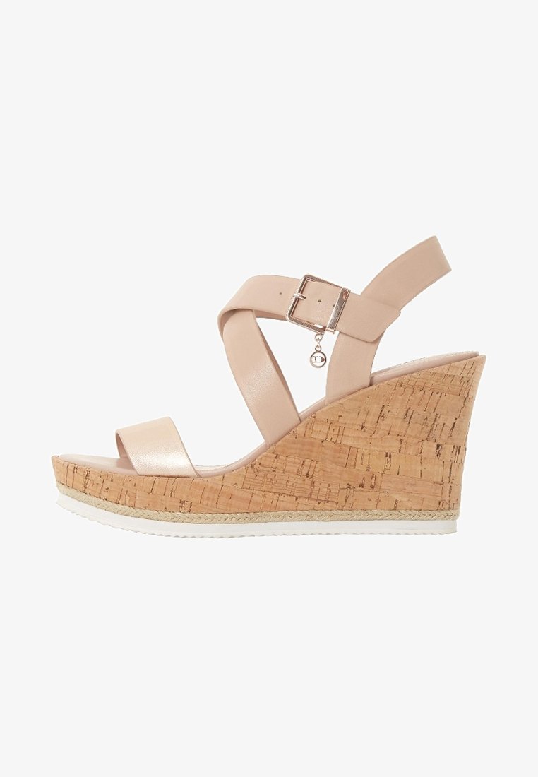 Sandale compensée beige avec plateforme en liège, bride à la cheville avec boucle, et un petit pendentif rond suspendu à la boucle.
