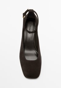 Black suede high-heeled shoe with a square toe and a slim ankle strap. Smooth inner lining with brand detail visible.