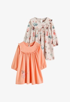 Dos vestidos de manga larga para niños pequeños, uno melocotón con un ratón y cuello con volantes, el otro crema con patrones coloridos de castillos y relojes y cuello con volantes.