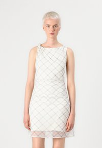 Vestido sin mangas con escote drapeado, hecho de un tejido ligero en color crema con un sutil patrón de cuadros y un dobladillo transparente.