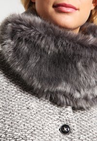 Grijze en witte textuurjas met een grote, zachte grijze bontkraag. Bevat een ronde zwarte knoop en zachte stofdetails.