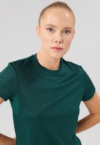 Green short-sleeve athletic t-shirt made of breathable fabric, featuring a round neckline and textured surface.