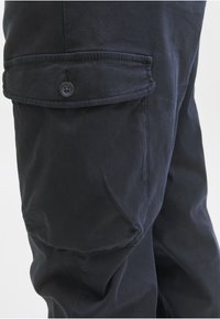 Granatowe spodnie cargo z teksturowanej tkaniny, z boczną kieszenią na guzik oraz wzmocnionymi szwami dla większej trwałości.