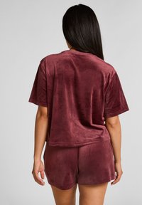 Bordeaux loungewear set van zacht, fluwelig materiaal. De top is met korte mouwen en heeft een relaxte pasvorm, gecombineerd met bijpassende shorts.