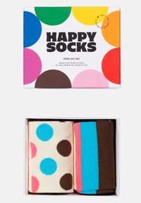 Σετ δώρου περηφάνειας που περιέχει δύο ζευγάρια ανδρικών κάλτσων. Ένα ζευγάρι έχει μεγάλα πουά σε ανοιχτό φόντο, ενώ το άλλο έχει έντονες ρίγες.