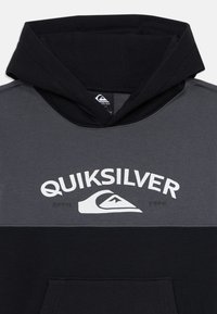 Sudadera con capucha con bloques de color negro y gris oscuro, logo de Quiksilver y texto "Quiksilver" impreso en blanco en el pecho.