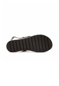 Suela de zapato de goma negra con surcos horizontales y punta redondeada. Presenta una superficie plana y una ligera curva hacia arriba en el talón.