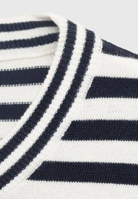 Marinblå och vit randig tröja med ribbad rund halsringning och texturerad stickning. Ränderna varierar i bredd och skapar ett iögonfallande mönster.