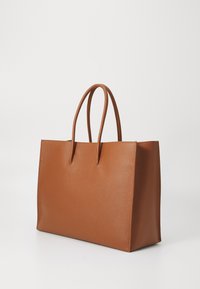 Brown leather tote bag with a structured design, flat base, two rounded handles, and a pebbled texture. No visible hardware or accents.