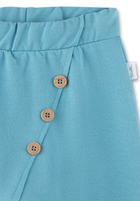 Light blue skirt in soft fabric, featuring a gathered waistband, a side button closure with four wooden buttons, and a diagonal seam detail.