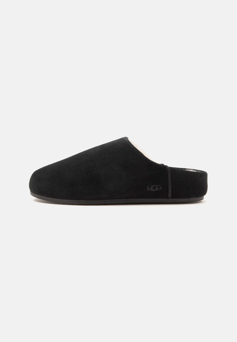 Chausson UGG noir à enfiler avec bout fermé, petit talon et extérieur en daim doux sur fond blanc uni.