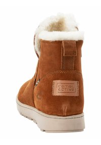 Braune Wildleder-Ankle-Boots mit einem weichen weißen Fellkragen, strukturiertem Rücken und einem beigen Logo-Patch. Verfügt über eine flache Gummisohle für besseren Grip.