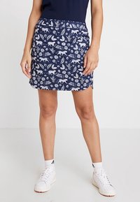 Námořnická modrá sukně s bílým vzorem zvířat a listoví, vyrobená z měkké látky, s přiléhavým střihem a bočním rozparkem.