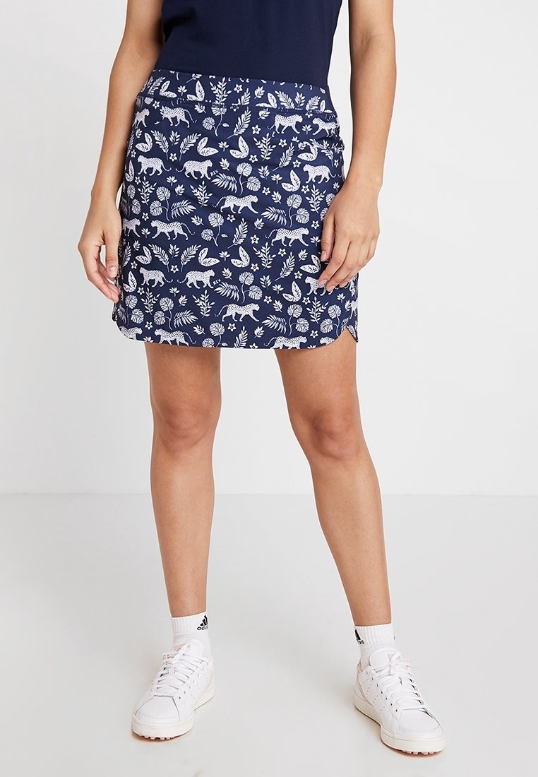 Námořnická modrá sukně s bílým vzorem zvířat a listoví, vyrobená z měkké látky, s přiléhavým střihem a bočním rozparkem.