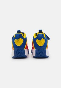 Chaussures de sport rouges et bleues avec une tige texturée, des accents jaunes et une semelle en caoutchouc blanche. Dispose d'une languette au talon pour un enfilage facile.