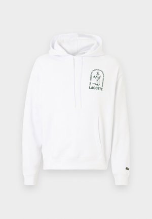 Weißer Hoodie mit einer Kängurutasche, Kapuze mit Kordelzug und grünem, aufgedrucktem Lacoste-Logo. Rippbündchen und Saum. Weiche Stofftextur.