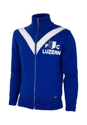 Blauwe trui met volledige ritssluiting, witte V-strepen, F C Luzern tekst, schildembleem op de borst, geribde boorden en hoge kraag.
