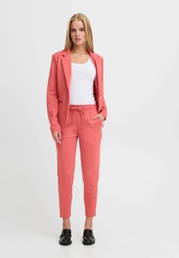 Korallblazer med matchande joggers, båda i en mjuk bomullsblandning. Slät textur, figursydd design och dragsko i midjan på byxorna.