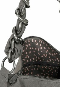 Bolso de mano gris con una asa de cadena metálica gruesa, tejido texturizado y un forro interior de lunares. Presenta un bolsillo con cremallera.