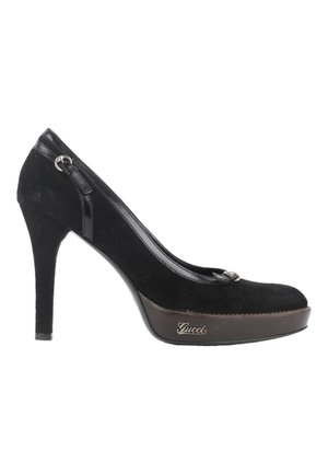Escarpin à talon haut en daim noir avec semelle plateforme et logo Gucci sur le côté, avec un petit détail de boucle près du talon.