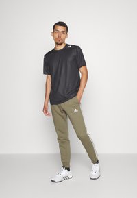 adidas Sportswear ESSENTIALS TAPERED CUFF 3-STRIPES  - Treniņtērpa apakšdaļas - olive strata