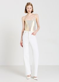 Camisola dorata metallica, jeans bianchi a vita alta e gamba larga, texture liscia, hardware minimale, décolleté bianchi a punta, sfondo neutro.